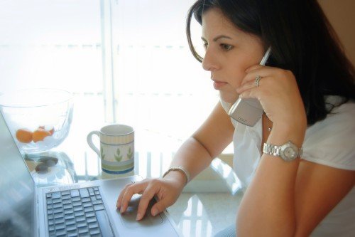 woman on phone using laptop