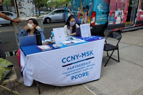 Two outreach staff at a PCORE table in the community 