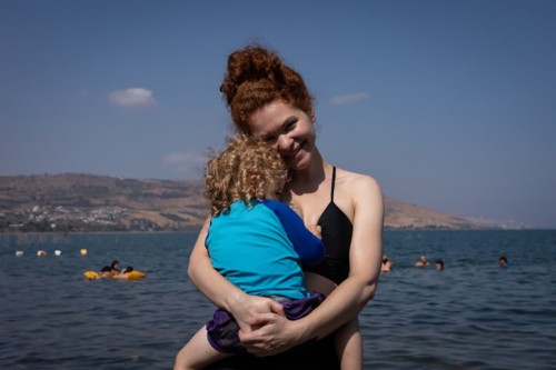 Sara Teichholtz stands in front of the water holding her son.