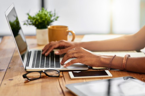 A woman's hands type on a laptop.