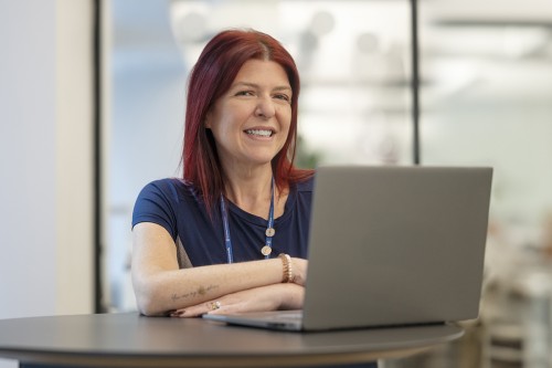 Nurse Lauren Kidd smiles while looking at a laptop computer
