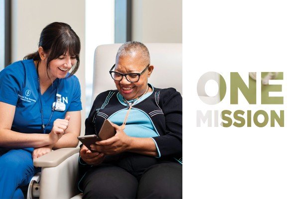 A smiling nurse and patient look at a cellphone